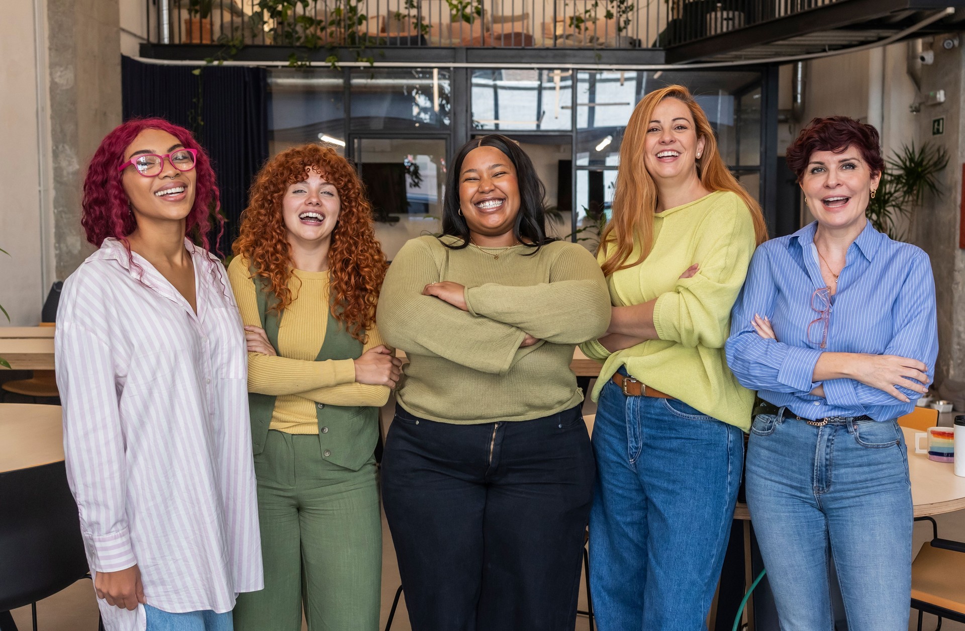Five businesswomen smiling with folded arms in office